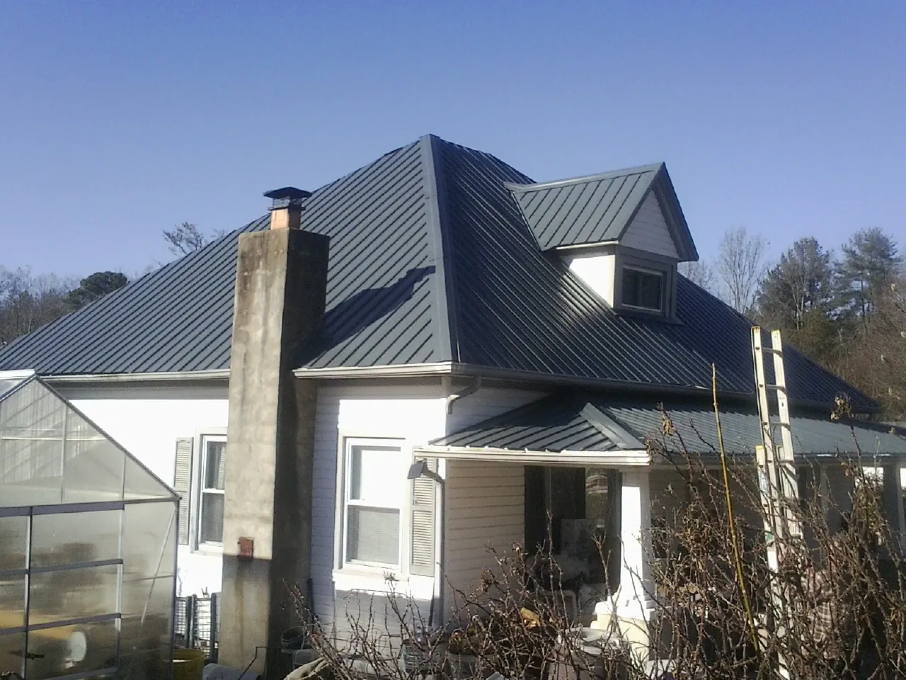 Dark blue standing seam metal roof on a white farmhouse with dormer — Slate & Tile Roof Repair by Roofing Brothers in Attalla