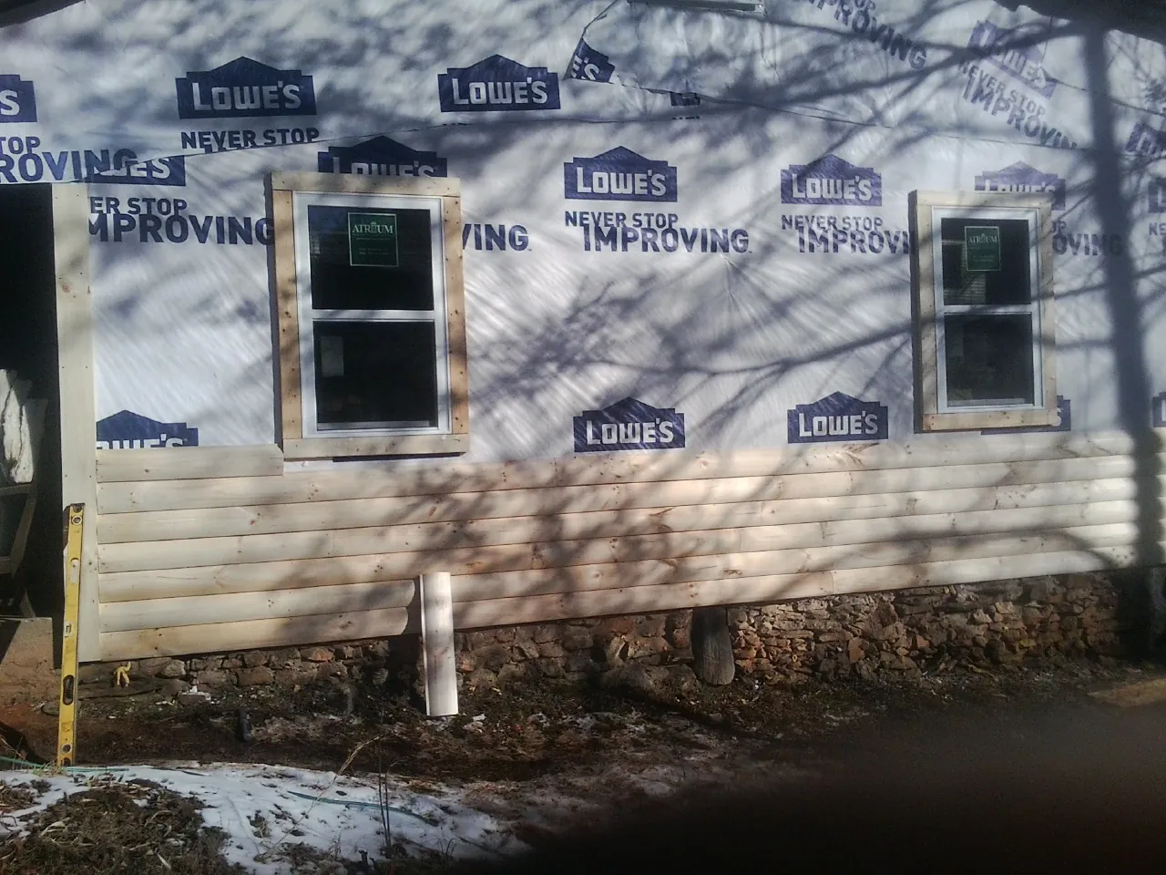 House wrap and new log siding going up on an exterior wall in Attalla
