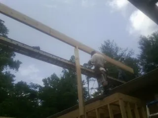 Carpenter setting a ridge beam over a new addition frame — Ice Dam Removal by Roofing Brothers in Attalla