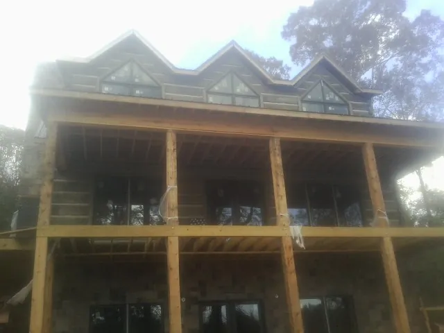 Dormers and porch framing on a large log home under construction — Roof Coating work by our crew in Attalla