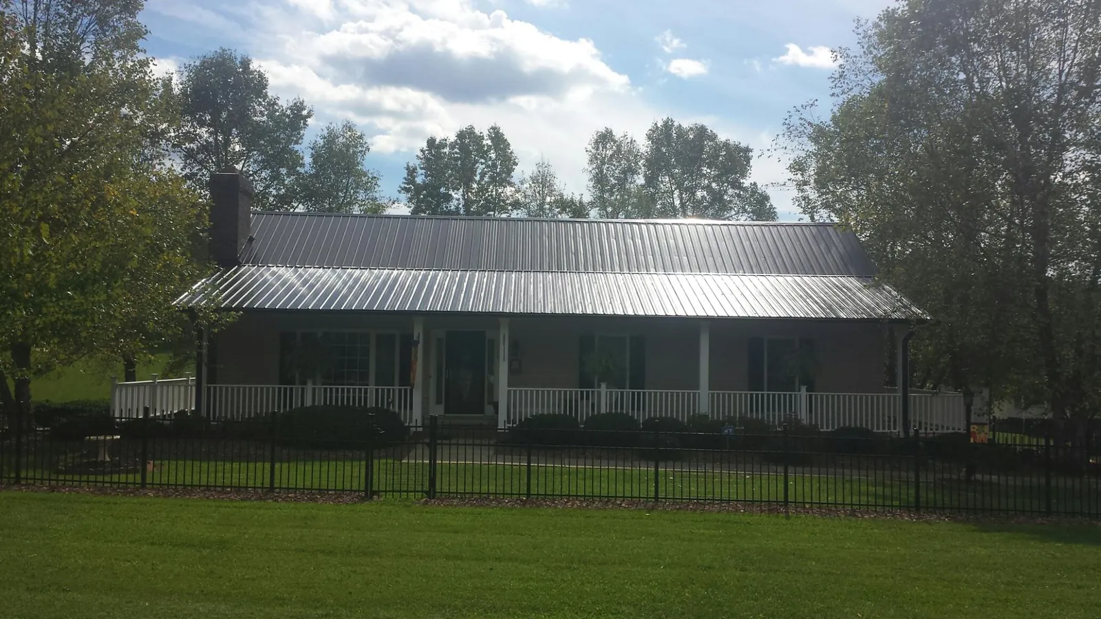 Gray metal roof on a brick ranch with a full width front porch — Gutter Guard Installation work by our crew in Attalla
