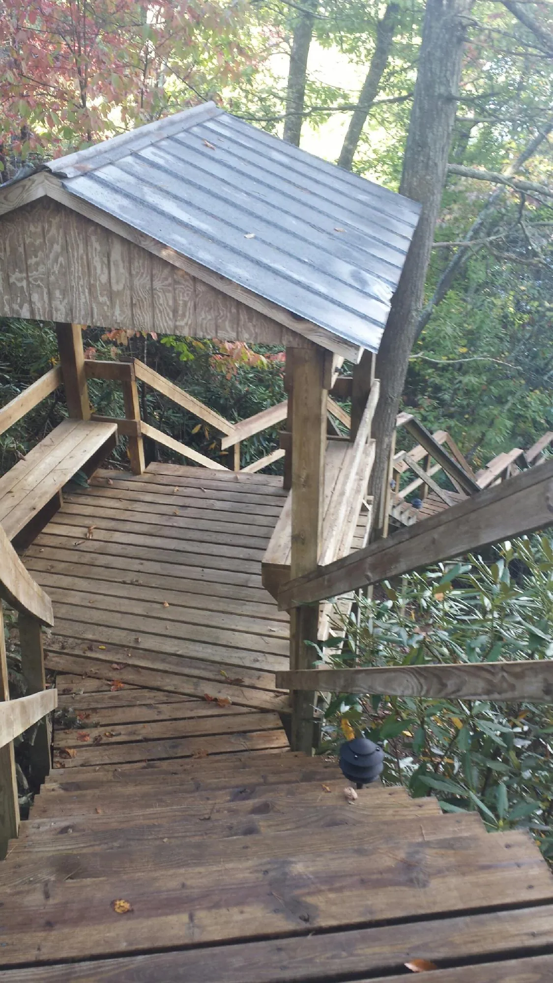 Metal roofed shelter over wooden steps on a wooded walkway — Skylight Repair & Installation work by our crew in Attalla