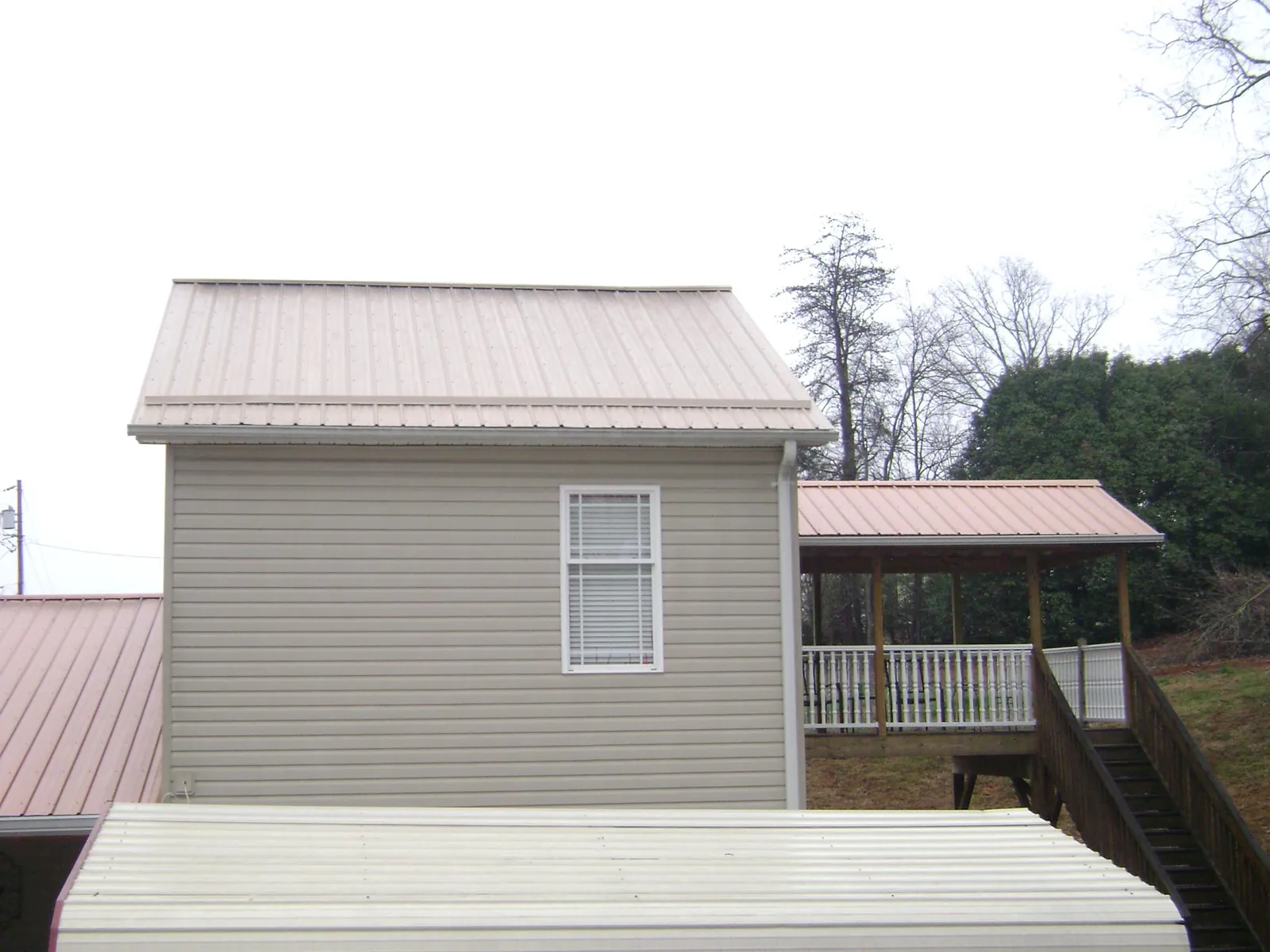 Tan metal roofs on a two story addition and attached porch, from a Roof Replacement job in Attalla
