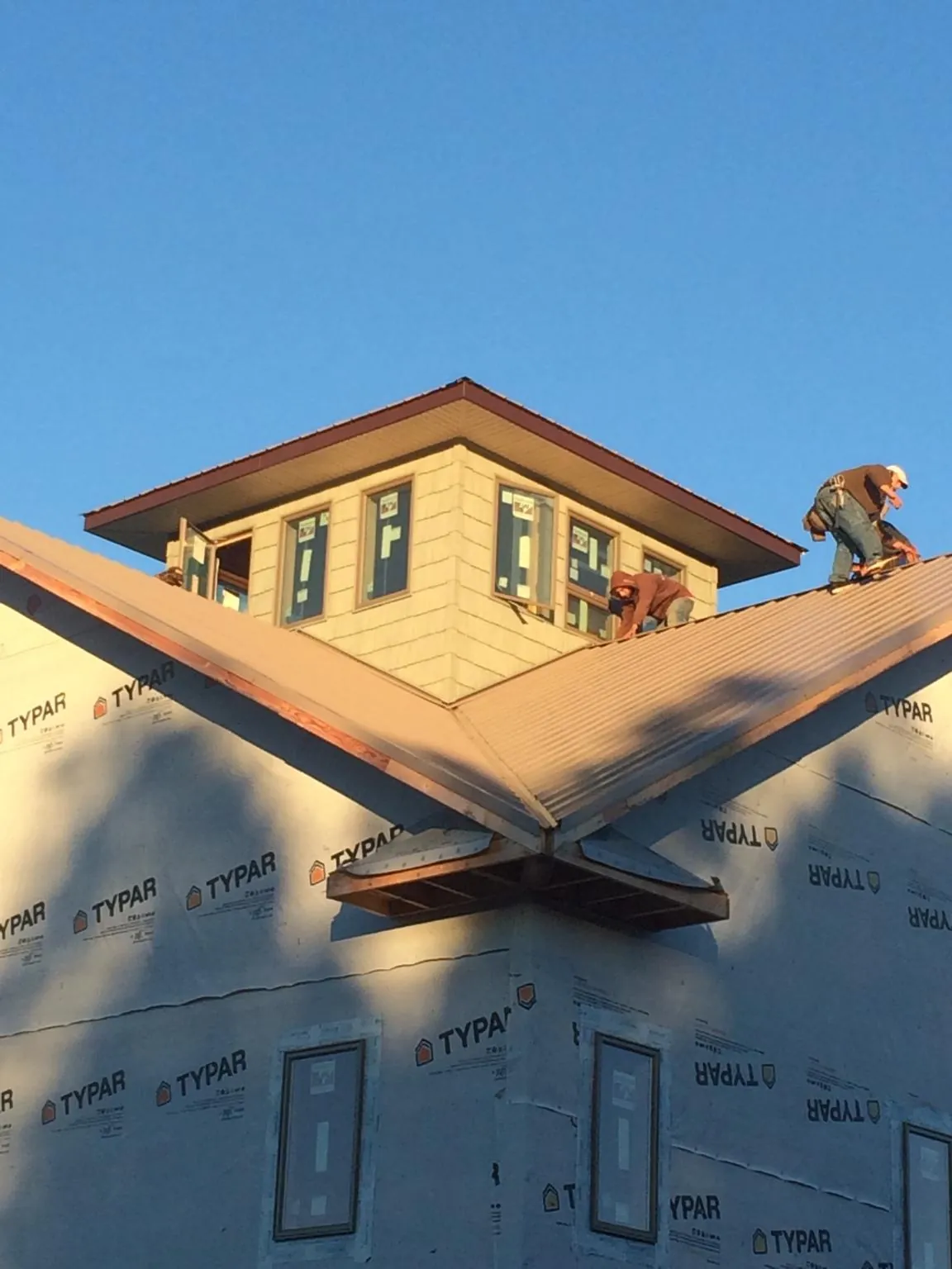 Roofers working around a rooftop cupola on a new metal roof at sunset — Roof Waterproofing in Attalla by Roofing Brothers